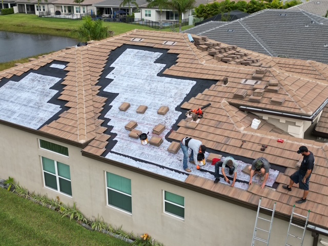 Mike McGilvary Roofing crew re-laying tile over freshly installed underlayment on a Palm Beach County home — a targeted repair that preserves most of the existing roof