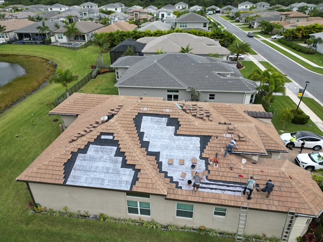 Aerial view of a South Florida tile roof mid-repair — the underlayment has been replaced in the failed sections while most of the original tile is preserved and re-set