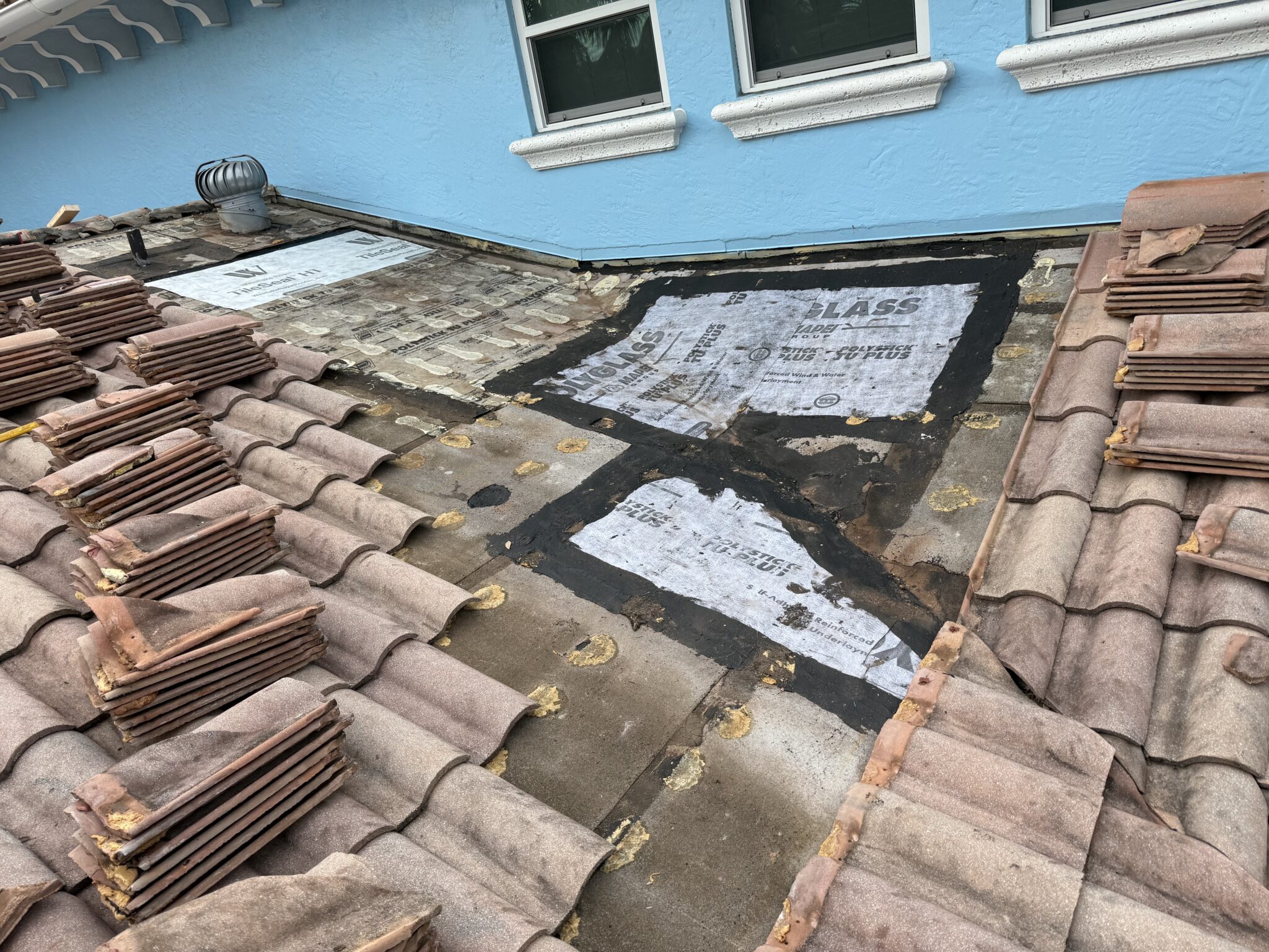 Gulf Stream tile roof showing several separate failed underlayment patches from repeated localized repairs