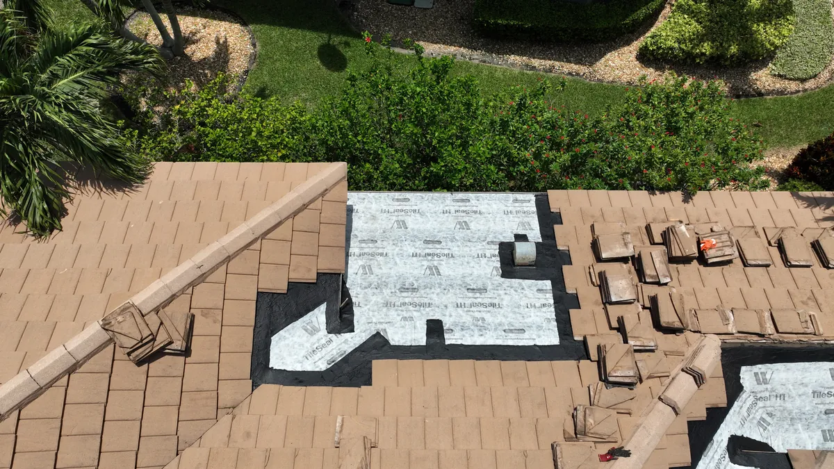 A roof section with new underlayment and existing tiles staged for reset