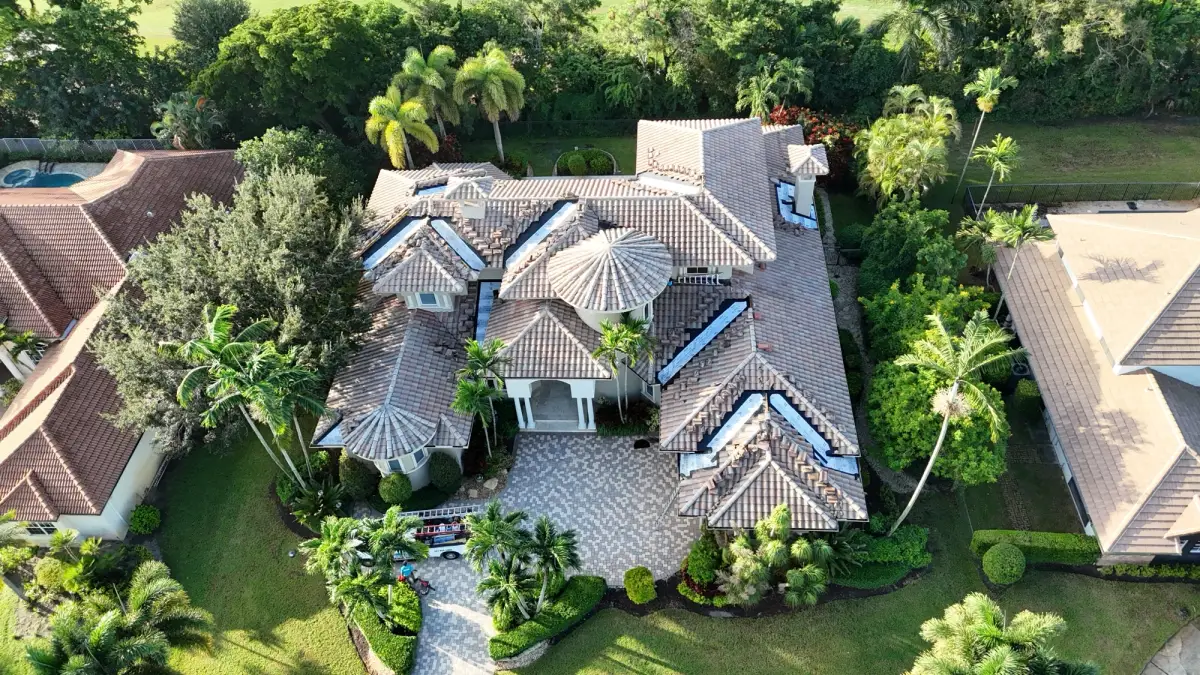 Aerial view of the front of a tile-roof home with valley repair areas visible and an MMR work truck in the driveway.