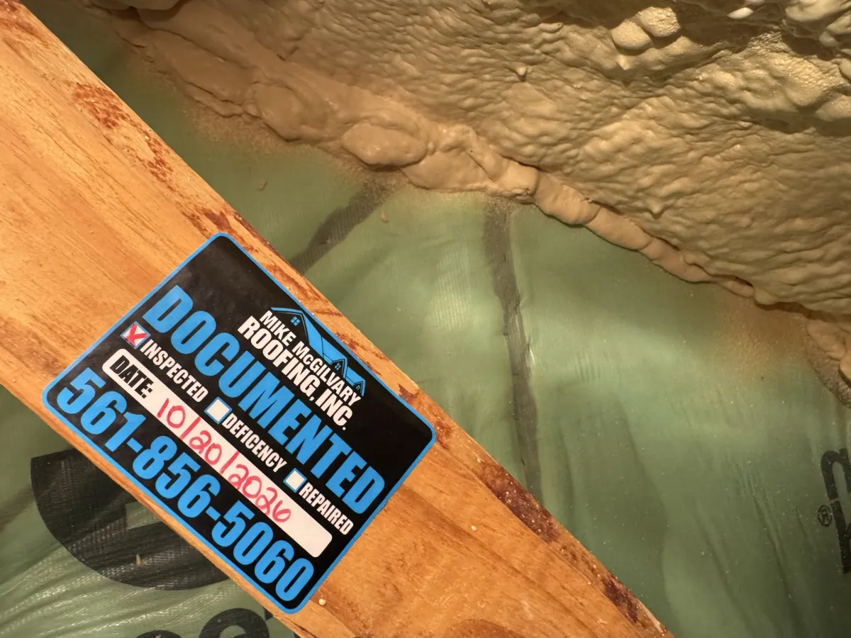 MMR Documented tag on a wood rafter beside spray foam insulation and roof underlayment.