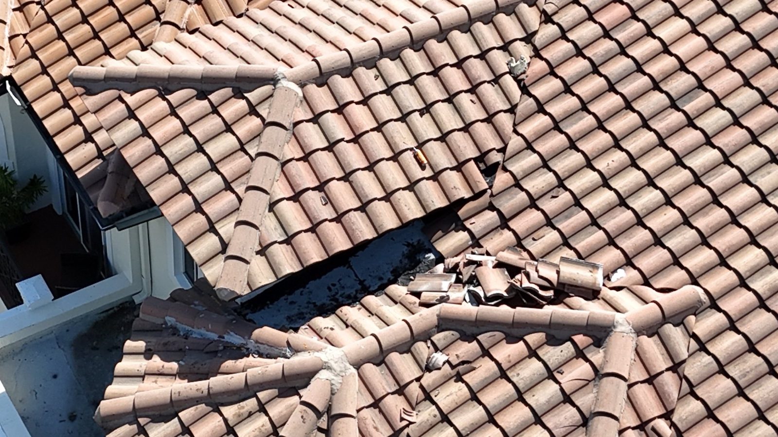 Exposed patch area and loose broken tile at a tile roof junction