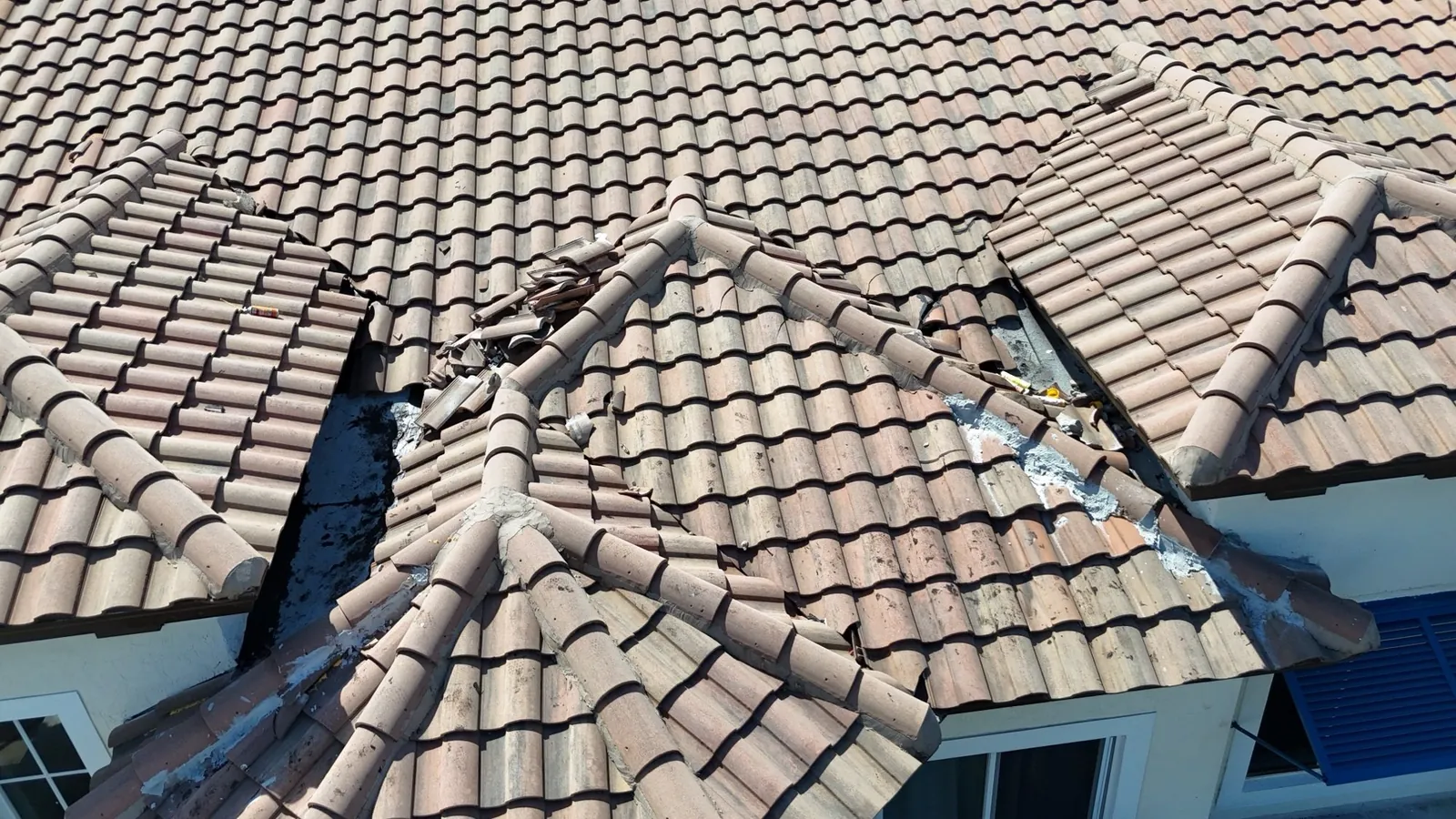 Two open roof junctions with loose tile on a townhome roof