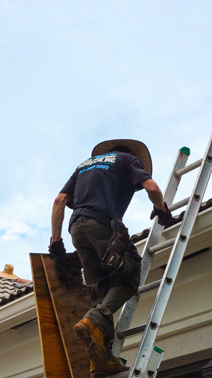 A Mike McGilvary Roofing crew member climbing a ladder onto the roof with materials