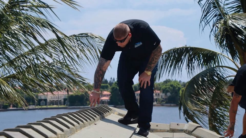 Roofing contractor inspecting the ridge of a tile roof at a waterfront home