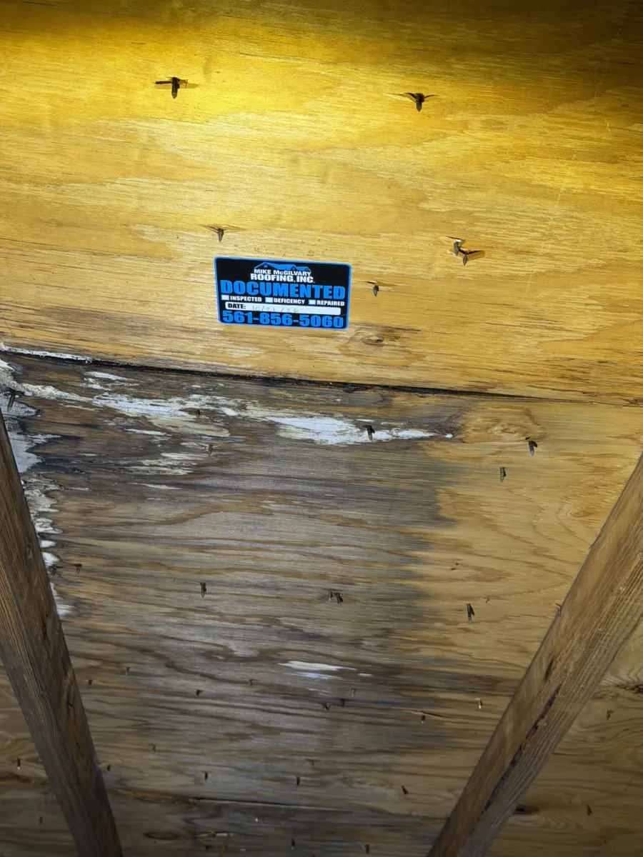 MMR Documented tag dated October 21, 2026, on plywood roof decking above dark water staining in an attic.
