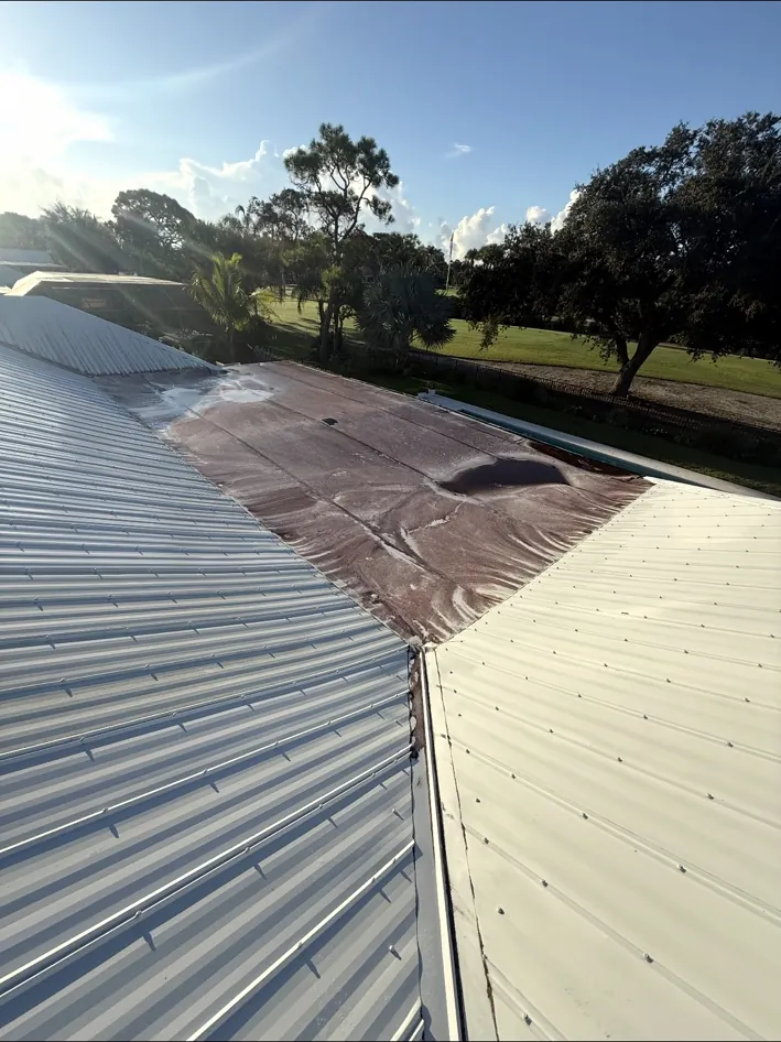 Before work: the flat section with brown staining between the metal roof slopes.