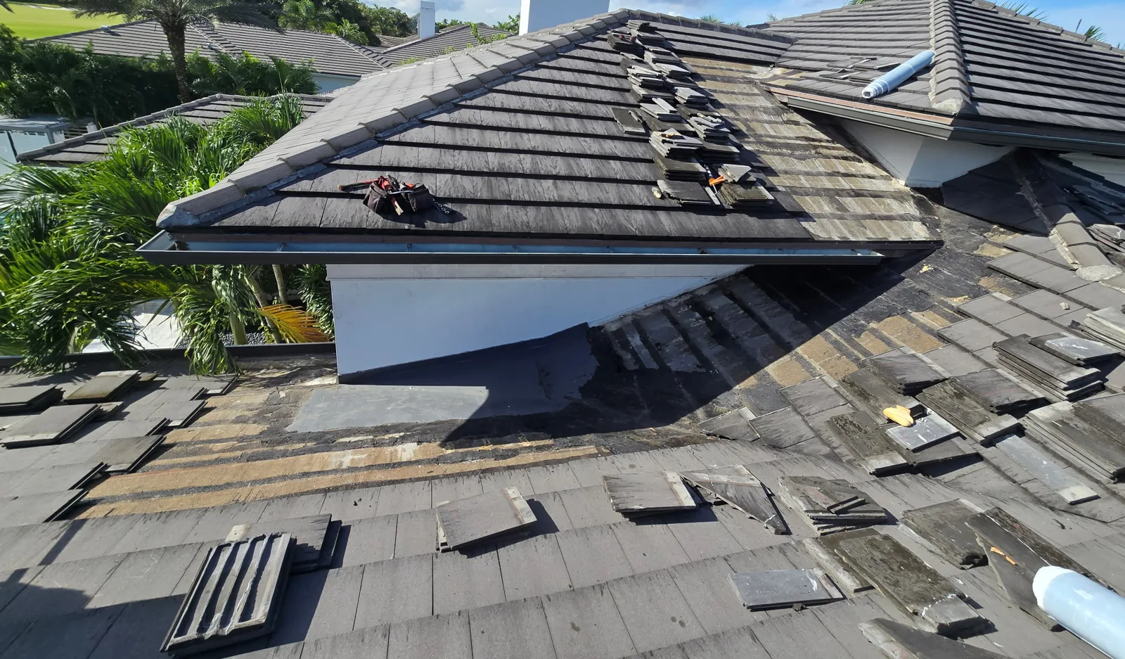 North Palm Beach flat-profile concrete tile roof opened at a failed repair area, tiles set aside for the section rebuild