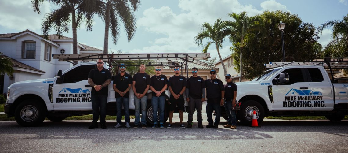 Mike McGilvary Roofing crew standing with the company's service trucks