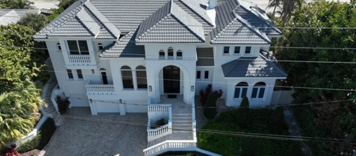 Drone view of a coastal home with a tile roof