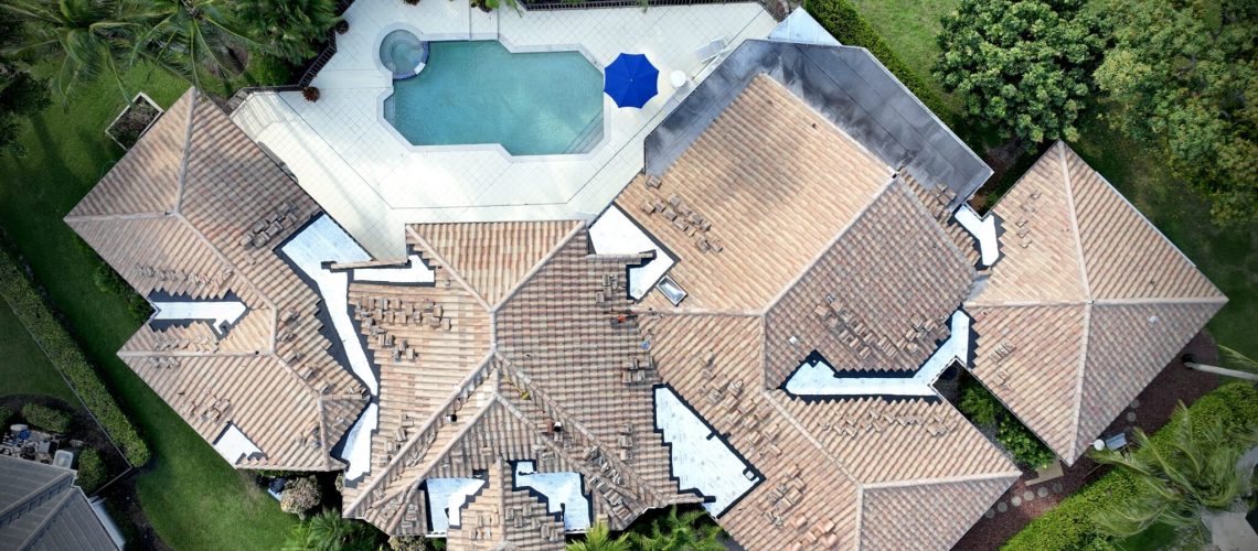 Drone view of an estate tile roof with sections opened for new underlayment