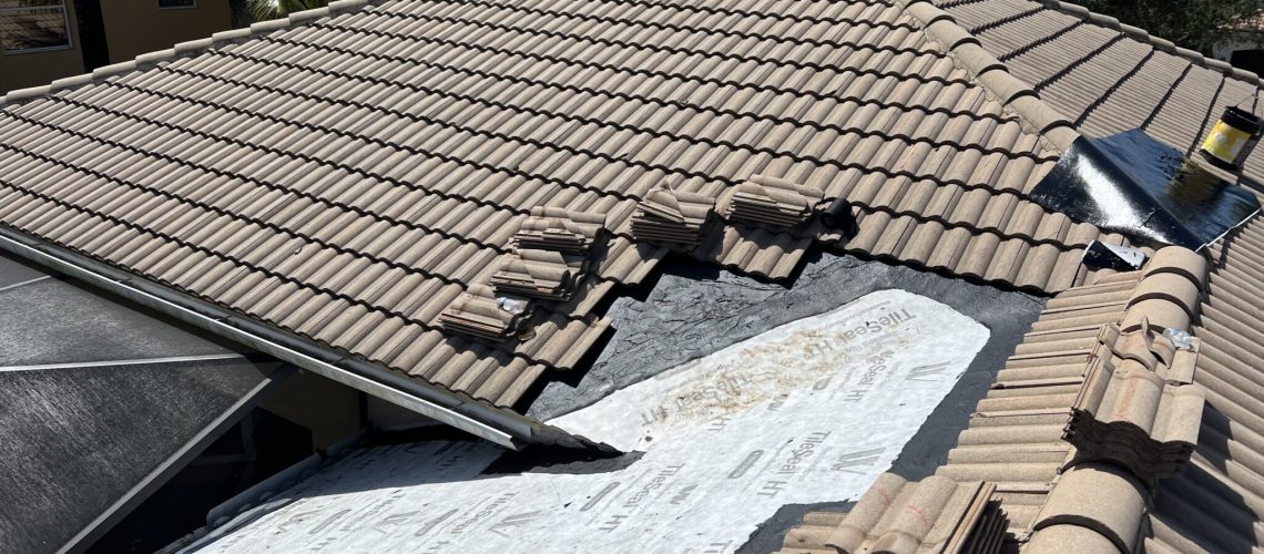 A concrete tile roof section opened down to new underlayment
