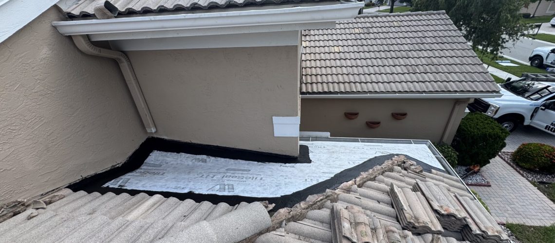 A tile roof opened where it meets a low-slope roof section