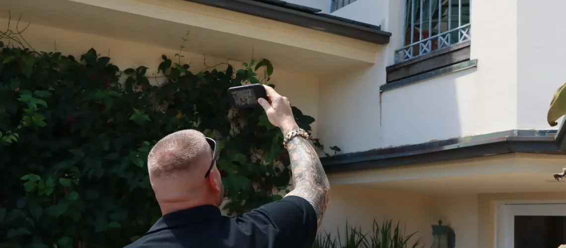 Mike McGilvary photographing and documenting an eave and fascia condition during a roof inspection