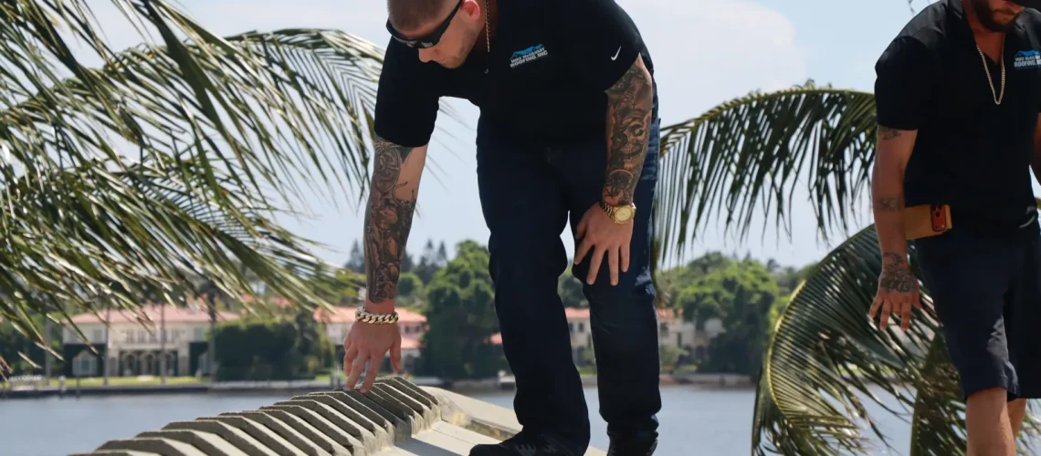 Mike McGilvary inspecting ridge tiles on a Palm Beach County waterfront tile roof while a crew member documents the property